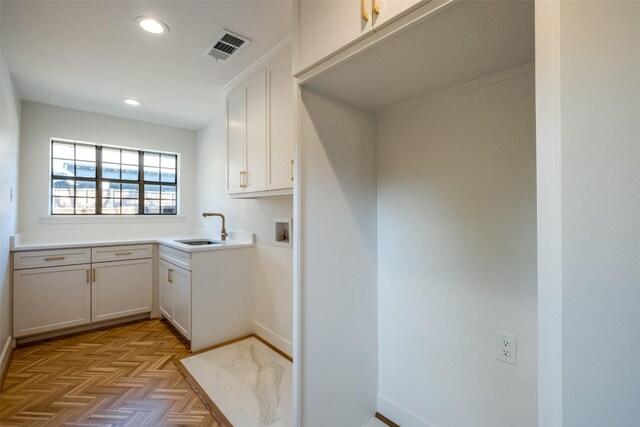 laundry room with hookup for a washing machine, light parquet floors, cabinets, and sink