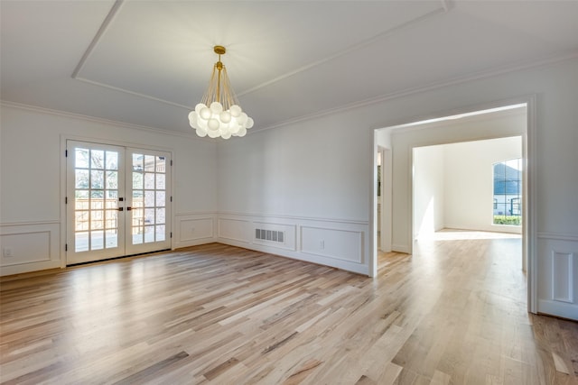 spare room featuring a chandelier, french doors, light wood-type flooring, and crown molding