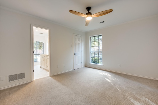 empty room featuring ceiling fan, light colored carpet, and crown molding