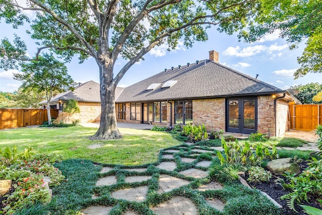 back of house featuring french doors and a lawn