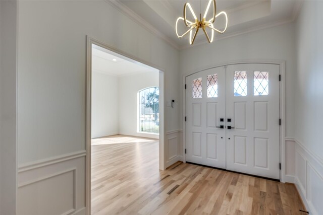 entrance foyer featuring crown molding, a notable chandelier, and light wood-type flooring