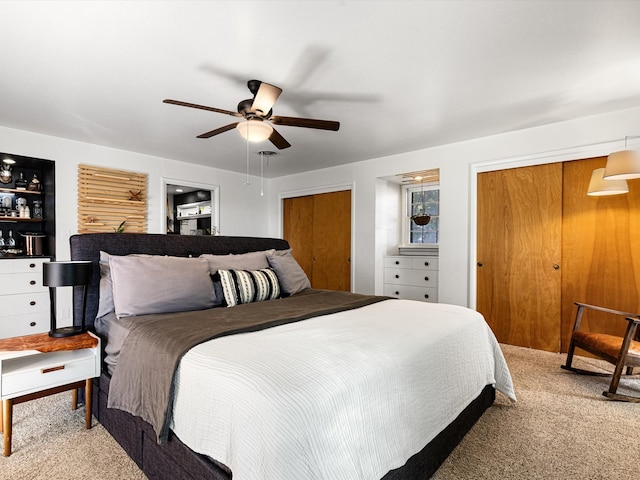 bedroom featuring two closets, carpet, and ceiling fan