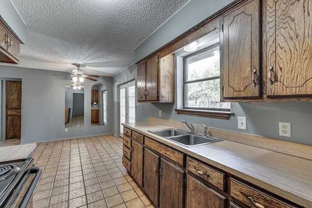 kitchen with sink, ceiling fan, range with electric stovetop, light tile patterned floors, and a textured ceiling