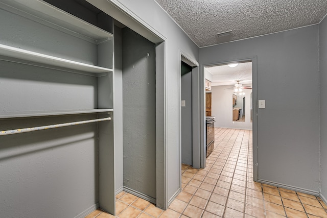 hall featuring light tile patterned floors and a textured ceiling