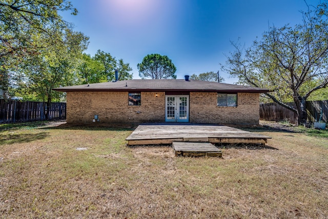 rear view of property featuring a lawn, french doors, and a deck