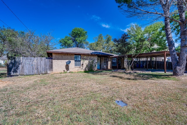 rear view of property with a carport and a yard