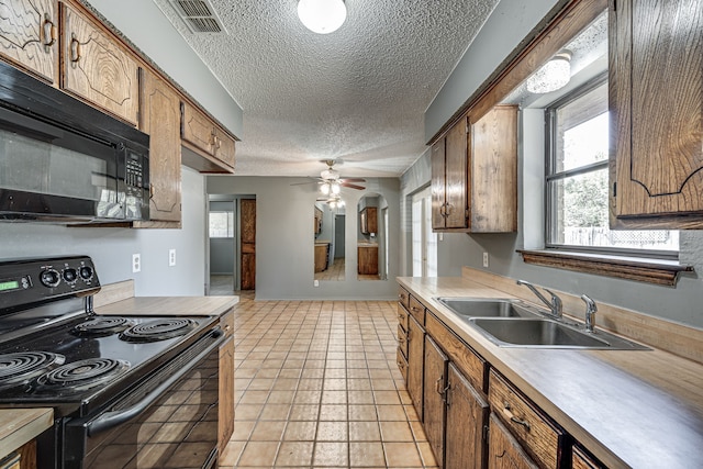 kitchen with black appliances, sink, ceiling fan, light tile patterned floors, and a textured ceiling