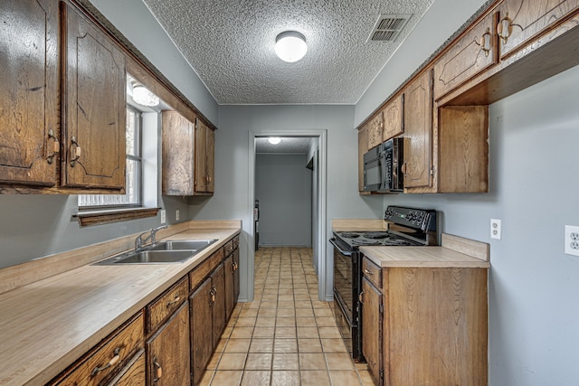 kitchen featuring black appliances, light tile patterned floors, sink, and a textured ceiling