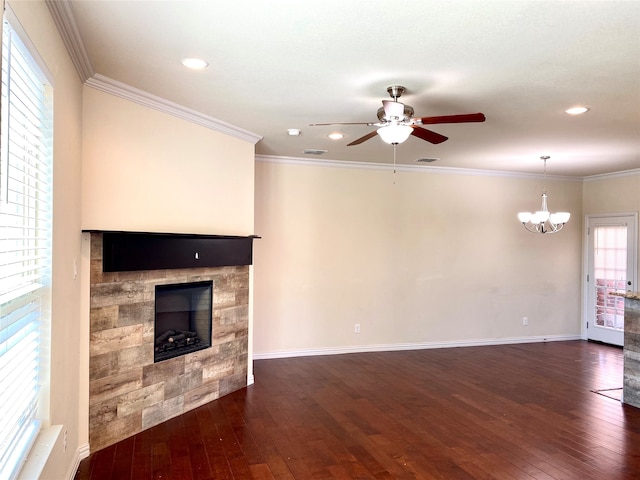 unfurnished living room with ceiling fan with notable chandelier, crown molding, a fireplace, and dark hardwood / wood-style floors