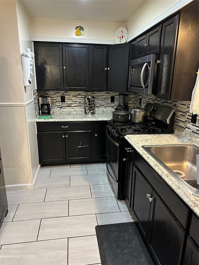 kitchen with light stone counters, tasteful backsplash, appliances with stainless steel finishes, and sink