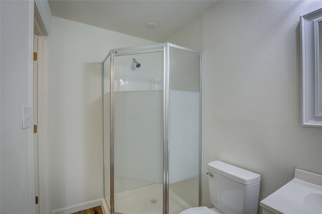 bathroom with toilet, an enclosed shower, and vanity