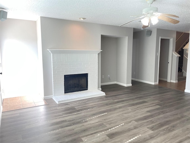 unfurnished living room with ceiling fan, dark hardwood / wood-style floors, a textured ceiling, and a fireplace