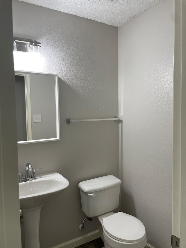 bathroom with toilet, sink, and a textured ceiling