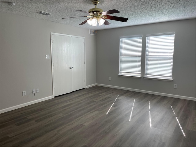 unfurnished bedroom with ceiling fan, dark wood-type flooring, a closet, and a textured ceiling