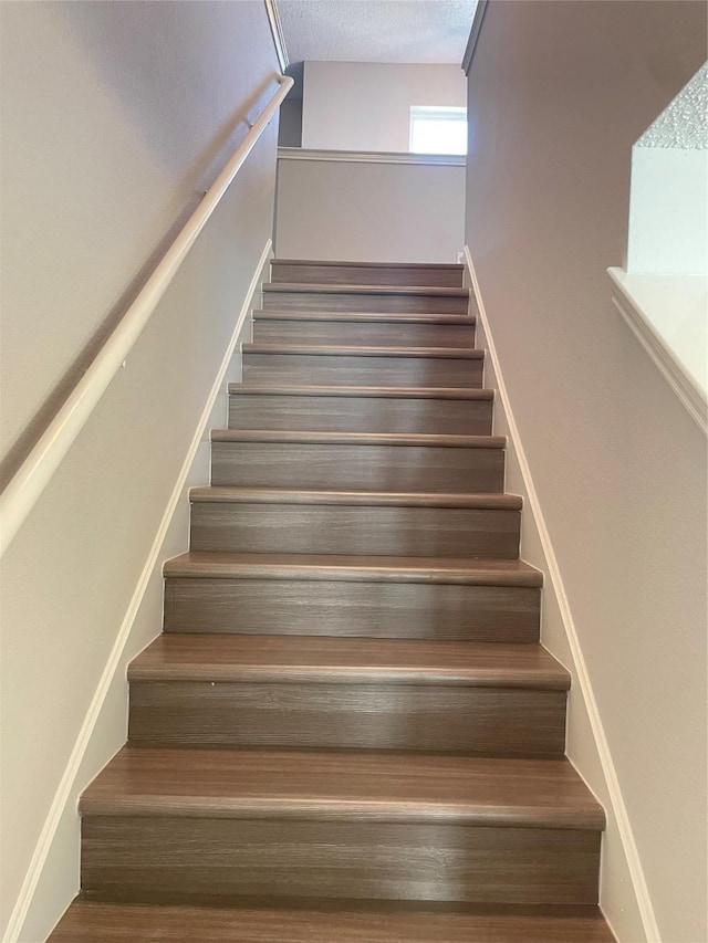 staircase featuring a textured ceiling