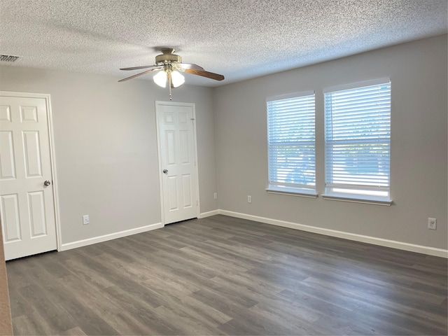 empty room featuring ceiling fan, dark wood-type flooring, and a textured ceiling