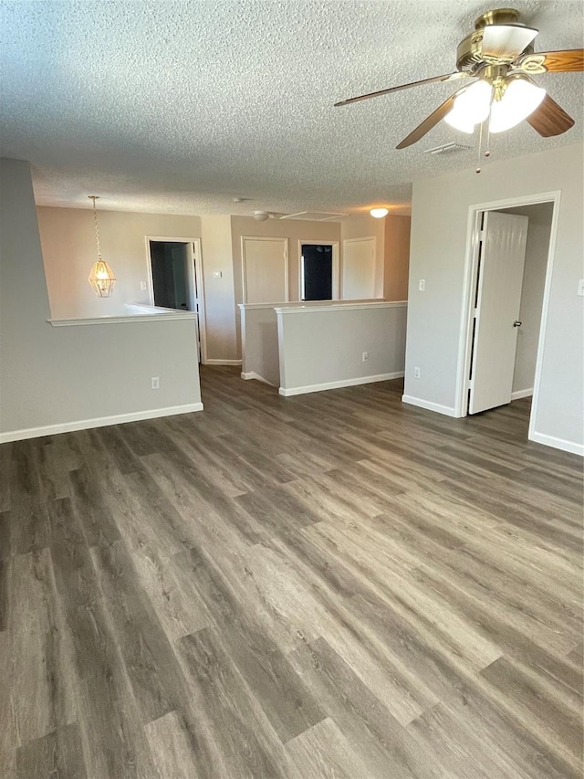 unfurnished living room with ceiling fan, dark hardwood / wood-style floors, and a textured ceiling