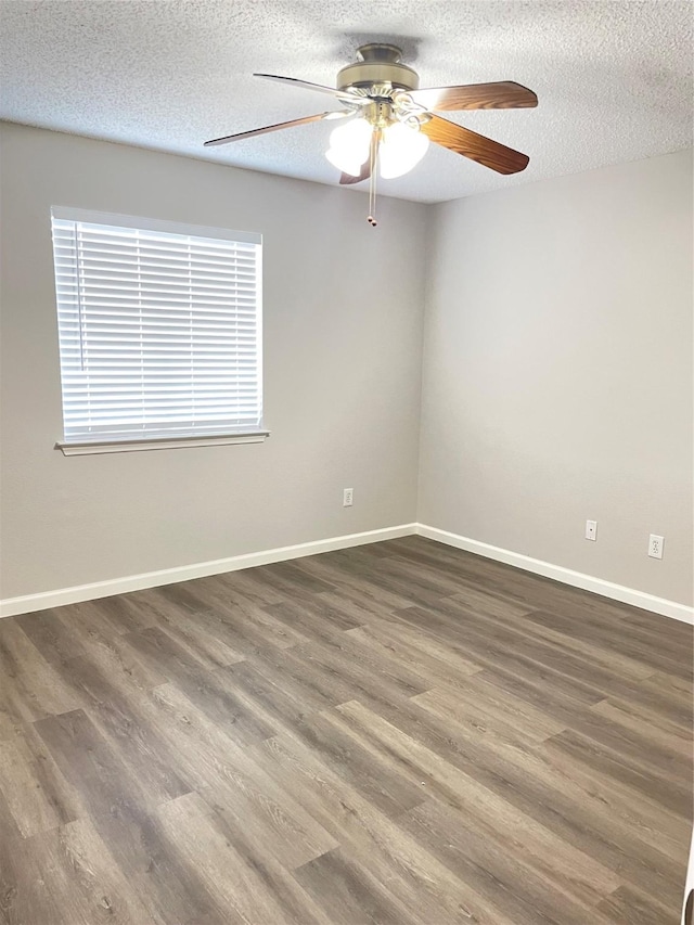 spare room featuring dark hardwood / wood-style flooring, ceiling fan, and a textured ceiling