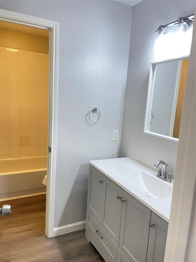 full bathroom with vanity, tiled shower / bath combo, wood-type flooring, and toilet