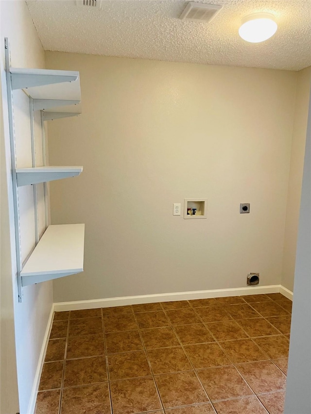 washroom with hookup for a washing machine, hookup for an electric dryer, dark tile patterned flooring, and a textured ceiling