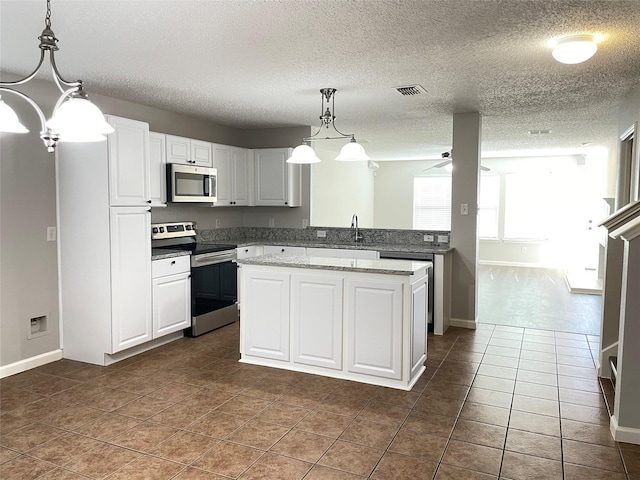 kitchen featuring appliances with stainless steel finishes, pendant lighting, white cabinetry, sink, and a center island