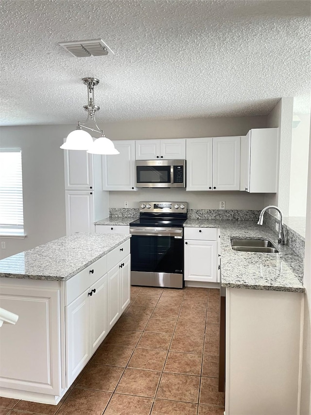 kitchen with sink, hanging light fixtures, stainless steel appliances, a center island, and white cabinets