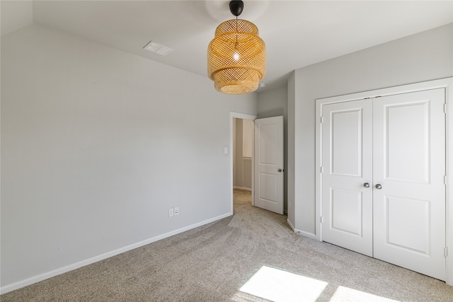 unfurnished bedroom featuring light carpet, a closet, and lofted ceiling