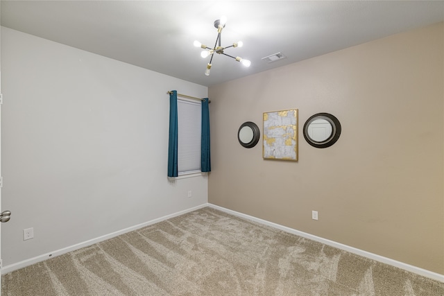 spare room featuring carpet and a chandelier