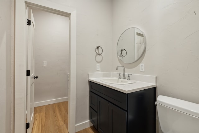 bathroom featuring vanity, hardwood / wood-style flooring, and toilet