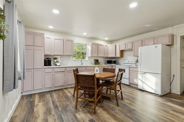 kitchen featuring dark hardwood / wood-style flooring, backsplash, white appliances, and sink