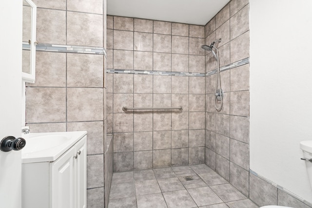 bathroom featuring a tile shower, tile patterned floors, vanity, and toilet