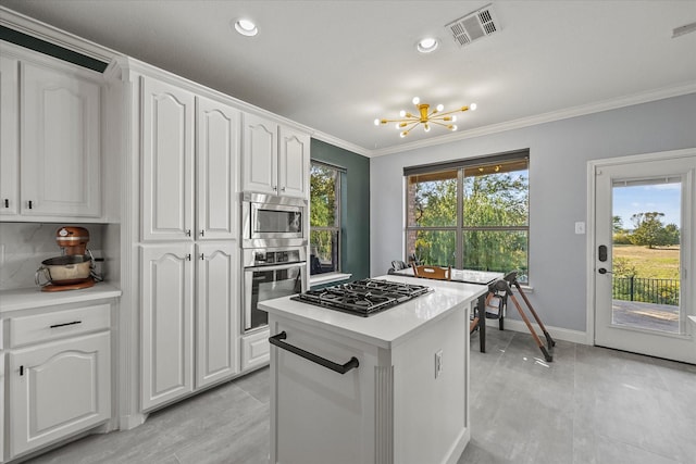 kitchen with a notable chandelier, appliances with stainless steel finishes, ornamental molding, and white cabinets