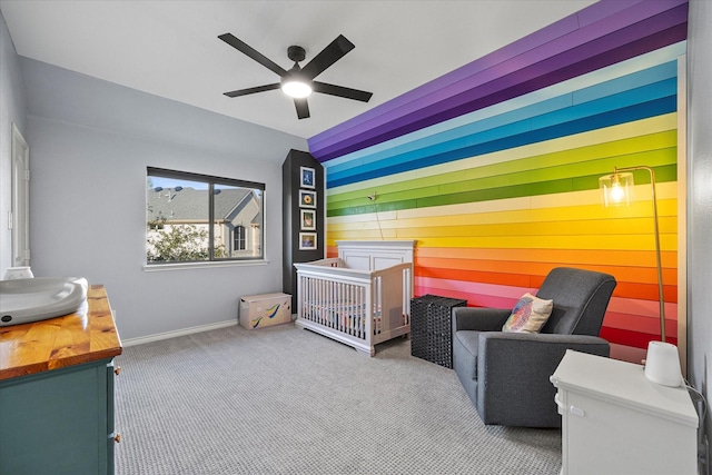 carpeted bedroom with a nursery area and ceiling fan