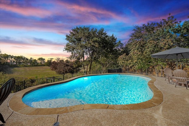 pool at dusk featuring a patio area