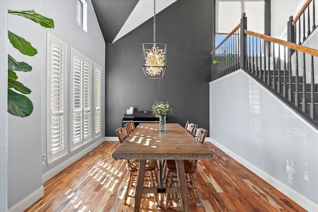 dining space with hardwood / wood-style flooring, plenty of natural light, a chandelier, and high vaulted ceiling