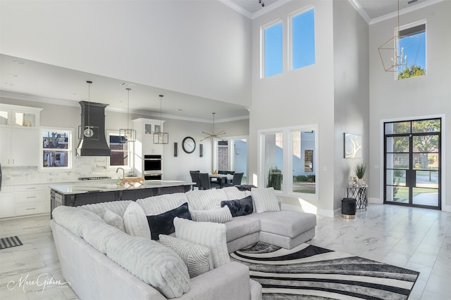 living room featuring a towering ceiling, ornamental molding, and ceiling fan with notable chandelier