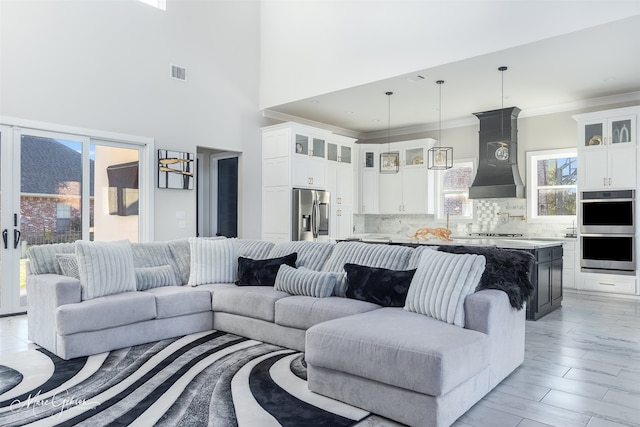 living room featuring ornamental molding, light hardwood / wood-style floors, and a towering ceiling