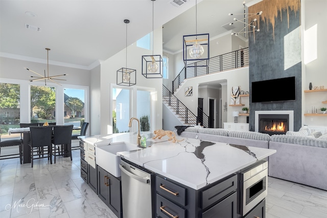 kitchen with an inviting chandelier, stainless steel appliances, a large fireplace, and sink