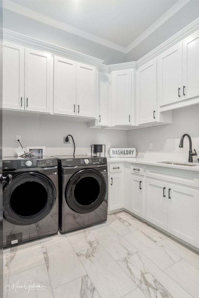 washroom with ornamental molding, cabinets, sink, and washer and clothes dryer