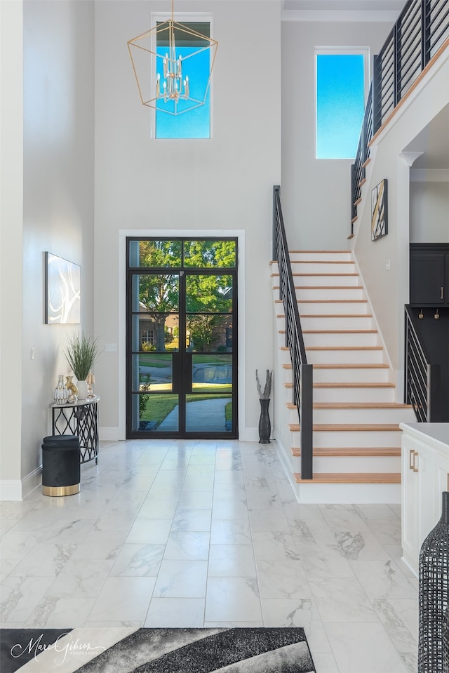 foyer with a high ceiling, crown molding, french doors, and plenty of natural light