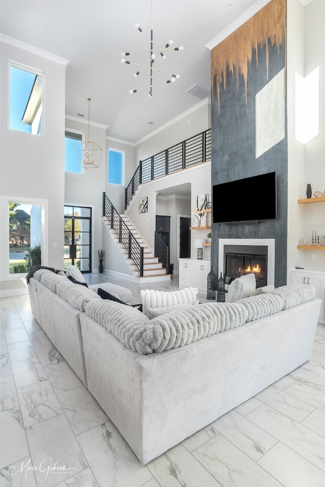 living room featuring crown molding, a notable chandelier, a high ceiling, and a fireplace