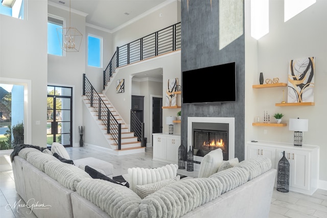 living room featuring a high ceiling, crown molding, a fireplace, and a chandelier