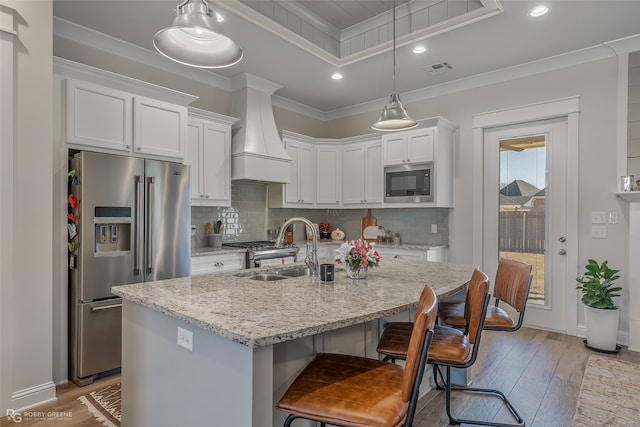 kitchen featuring a kitchen island with sink, sink, white cabinets, appliances with stainless steel finishes, and light hardwood / wood-style floors