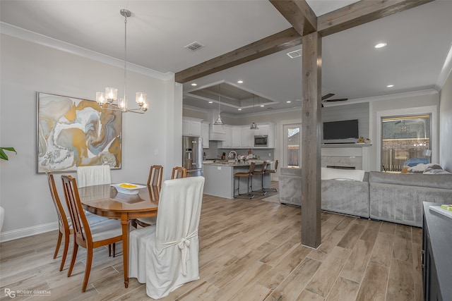 dining area featuring beam ceiling, a chandelier, ornamental molding, a fireplace, and light hardwood / wood-style floors