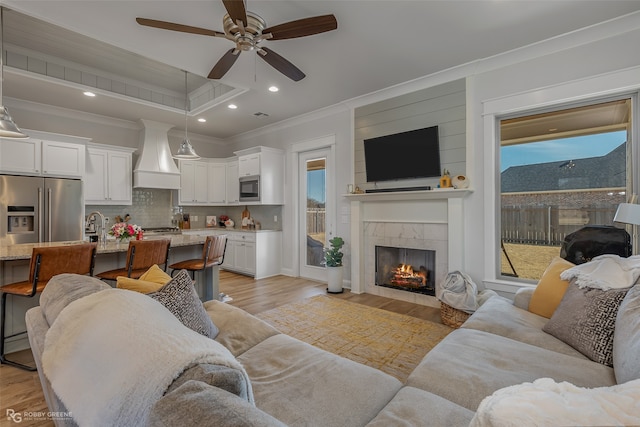 living room with crown molding, light hardwood / wood-style floors, a healthy amount of sunlight, and ceiling fan