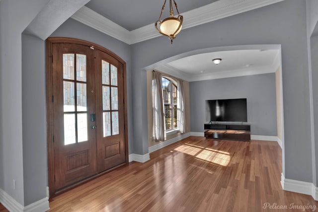 foyer entrance with french doors, crown molding, light wood-type flooring, and a wealth of natural light