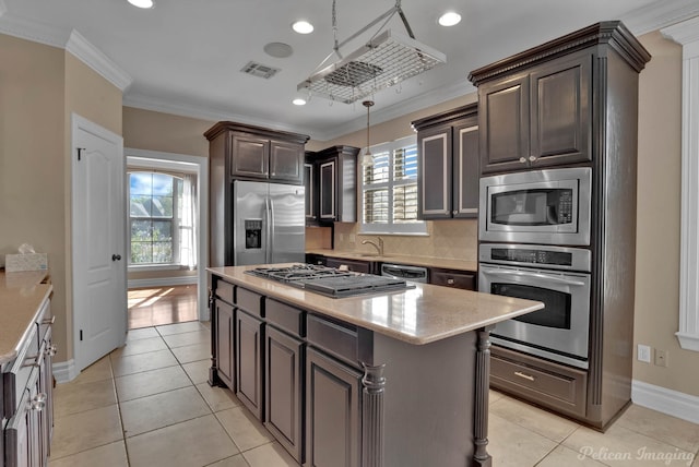 kitchen with a kitchen island, appliances with stainless steel finishes, crown molding, dark brown cabinetry, and decorative light fixtures