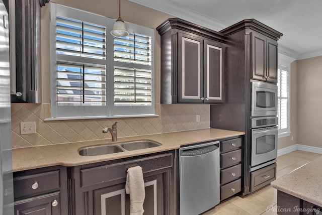 kitchen with sink, stainless steel appliances, pendant lighting, crown molding, and light tile patterned floors