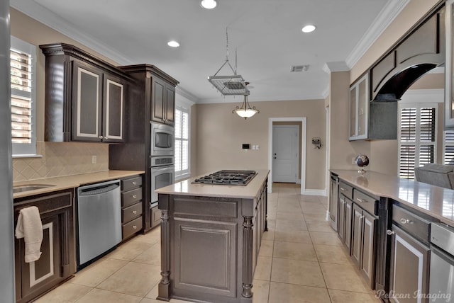 kitchen with light tile patterned floors, stainless steel appliances, crown molding, decorative light fixtures, and a center island