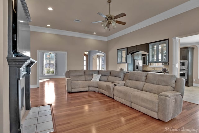 living room with crown molding, light hardwood / wood-style floors, and ceiling fan